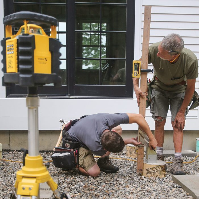 Two men using a laser to mark the top of each post.