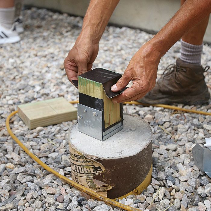 Hand wrapping post bases and post caps with flashing tape to protect from galvanic corrosion.