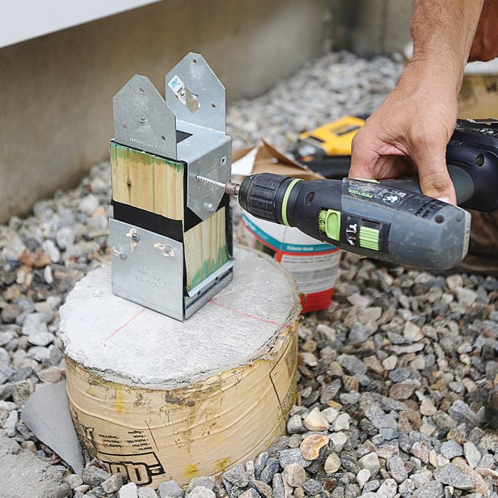 Hand using screwdriver to screw in post caps onto the posts.