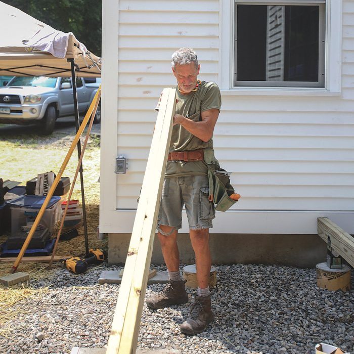 Man holding up a beam to make sure it's flat.