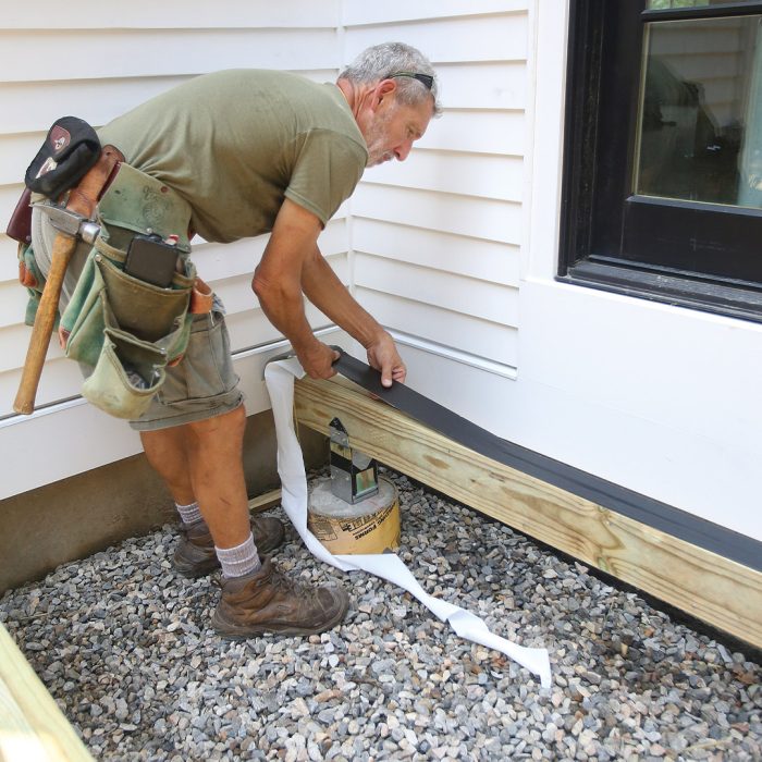 Man applying flashing tape to the top of a wooden beam.