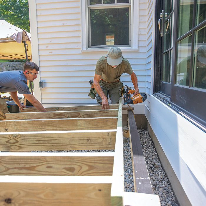 Man fastening joists of a freestanding deck with a nail gun.