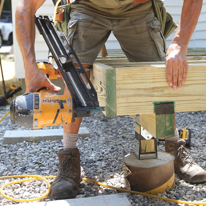 Man securing two boards together using a nail gun.