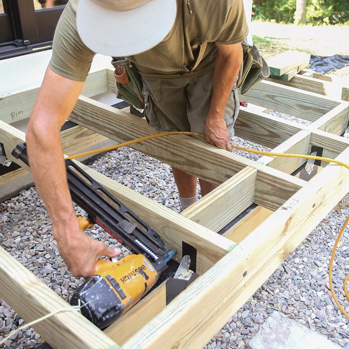 Man installing blocking over a freestanding deck beam using a nail gun.