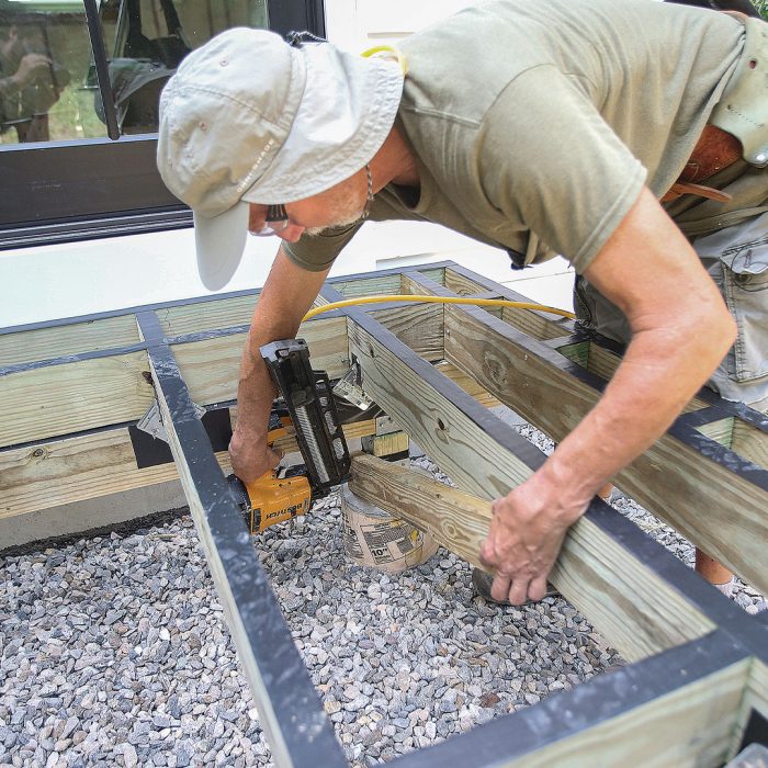 Man installing diagonal bracing using a nail gun.