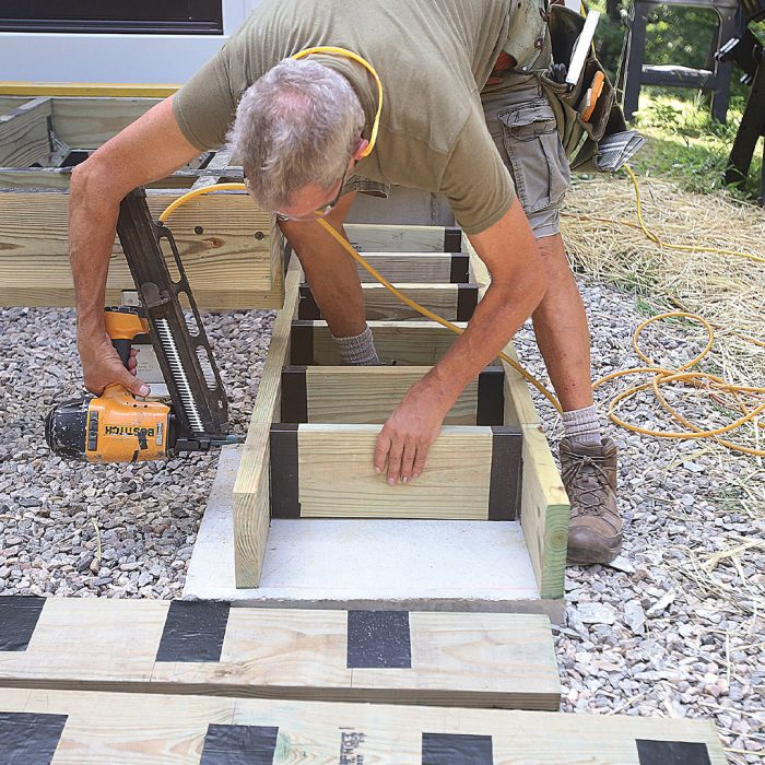 Man assembles stair boxes using a nail gun.