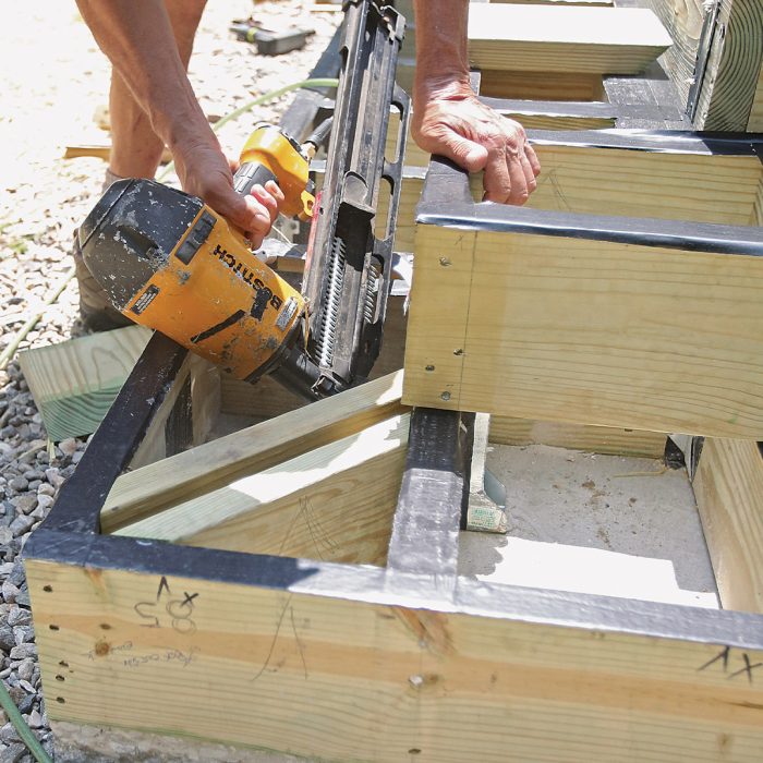 Man adds blocking to mitered deck boards using a nail gun.