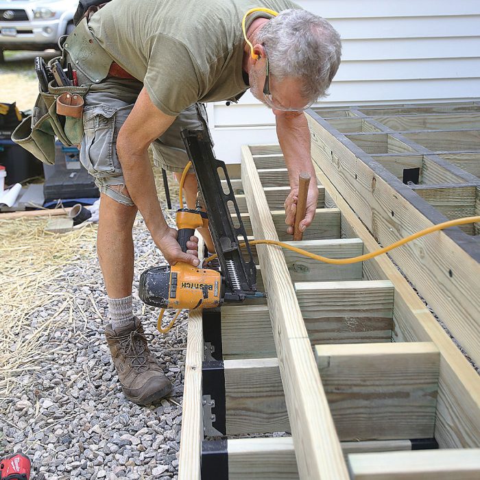 Man installs second set of box stairs above first set — the second set does not have joist hangers since it sits on and aligns with the boxes below.