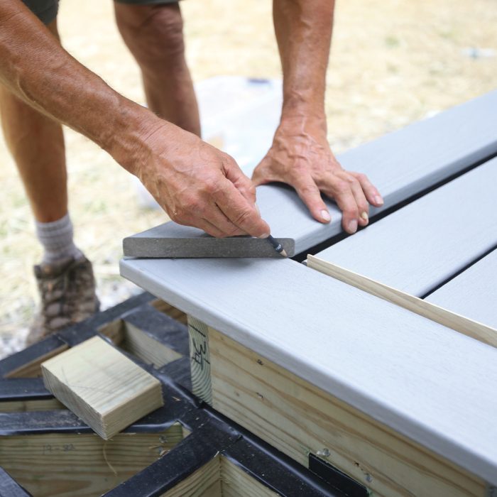 Man marks border boards for their miters using a pencil.