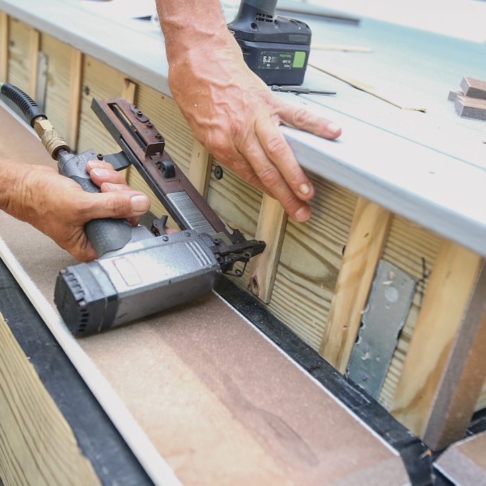 Man installs blocking to prevent water getting trapped behind boards.