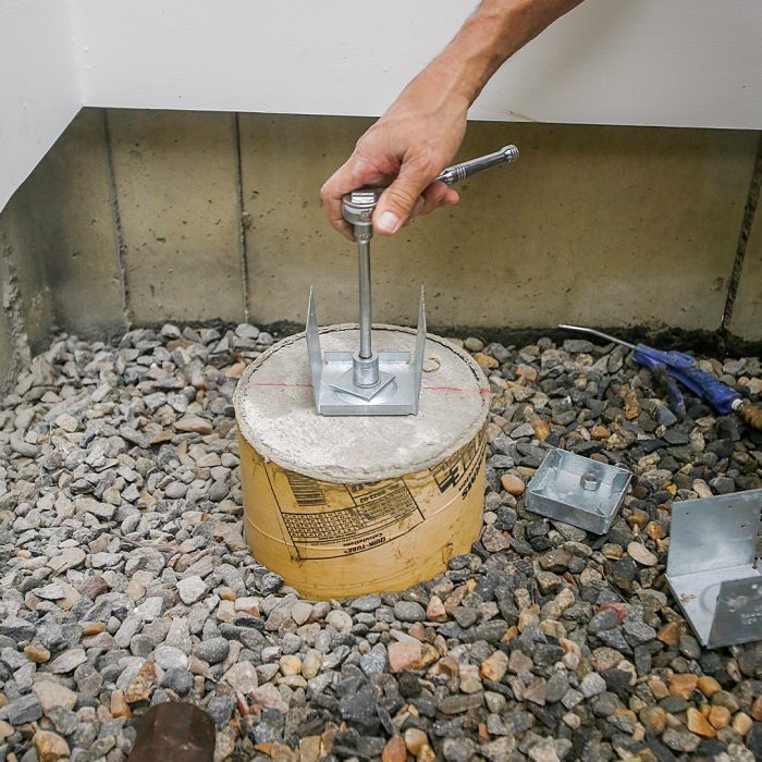 Hand screwing post-base anchors into the concrete base.