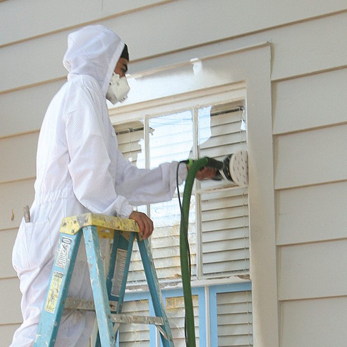 Man sanding primer to ensure paint sticks to the surface properly.