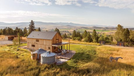 A home and grain silos surrounded by land